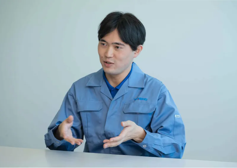 デスクに座り、身振り手振りを交えて笑顔で話すK.Kさん