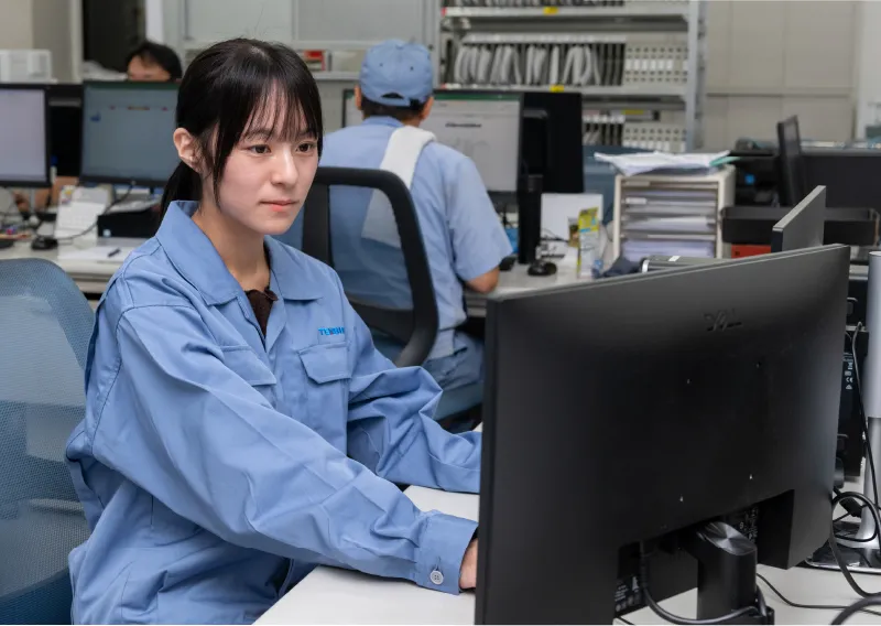 パソコンモニターや書類に向かい、真剣な表情で作業を行うM.Oさん