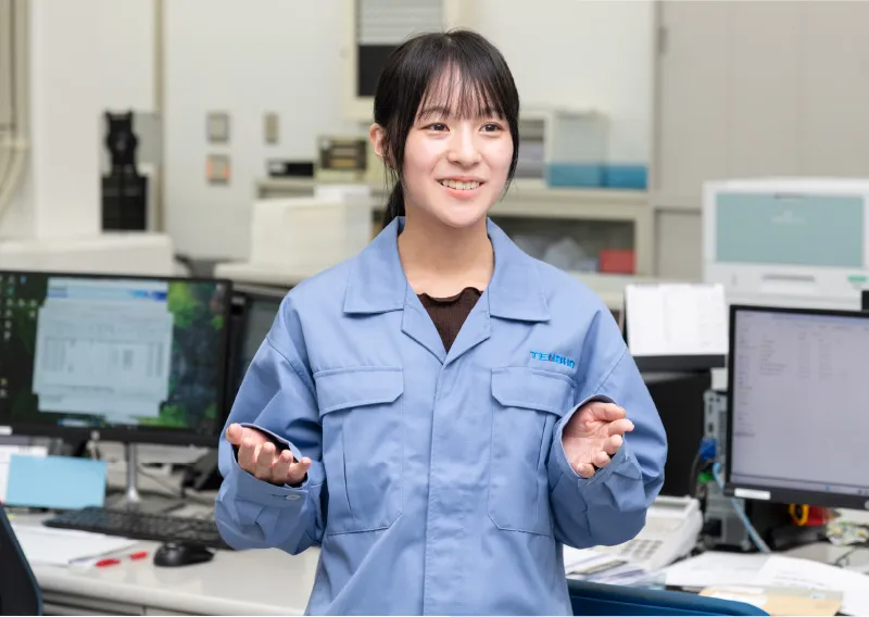 オフィス内で、穏やかな表情で立ちながら笑顔を見せるM.Oさん