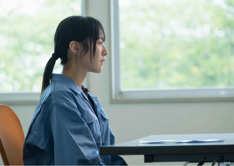 デスクに座り、横を向いて穏やかな表情を見せるM.Oさん