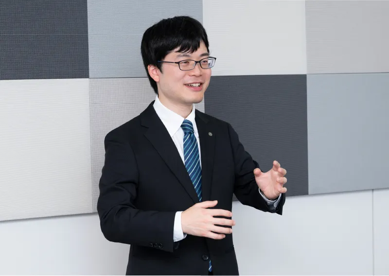 スーツ姿で笑顔を見せる管理本部 購買部のS.Tさん