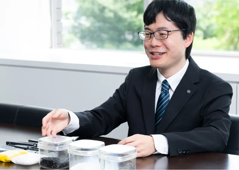 材料サンプルを手に笑顔を見せる管理本部 購買部のS.Tさん