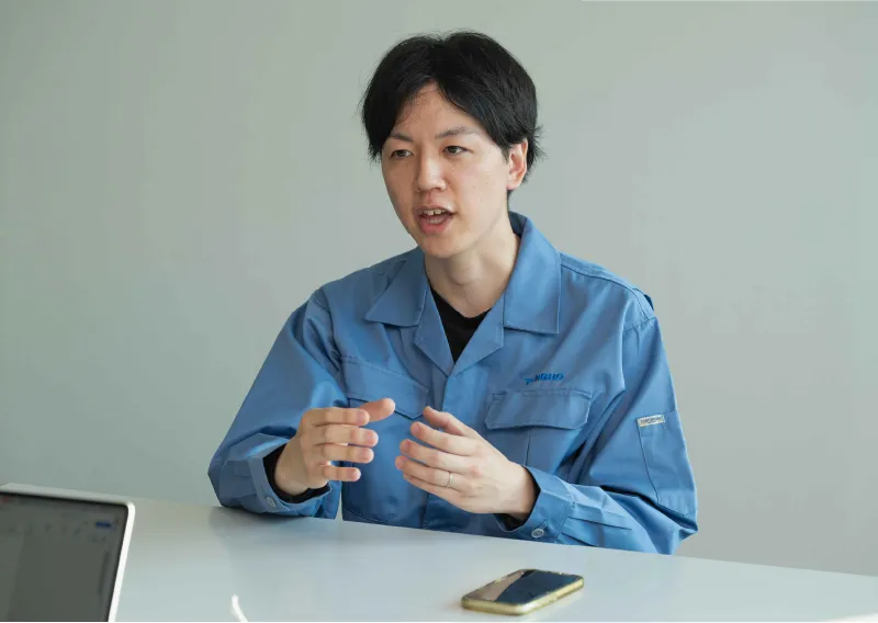 青い作業服を身にまとい、真剣な表情で話すD.Hさん