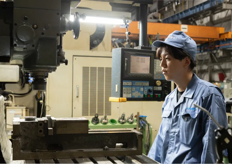 工場内で機械やモニターに向かい、作業を行うD.Hさん