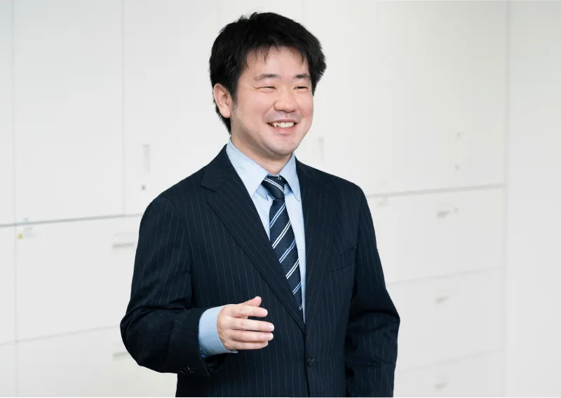 スーツ姿で笑顔を見せる総務人事部のT.Hさん
