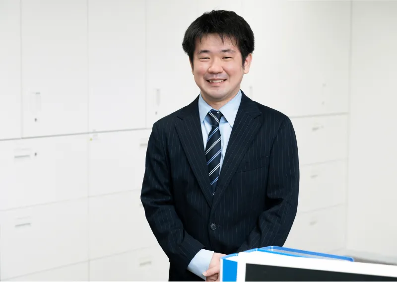 スーツ姿で笑顔を見せる総務人事部のT.Hさん