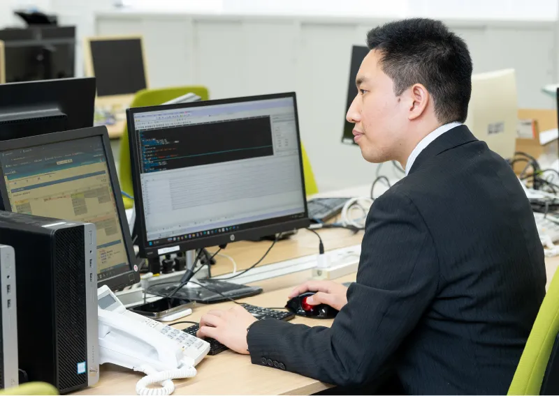 スーツ姿でパソコンに向かい作業をする管理本部 情報管理部のT.Sさん