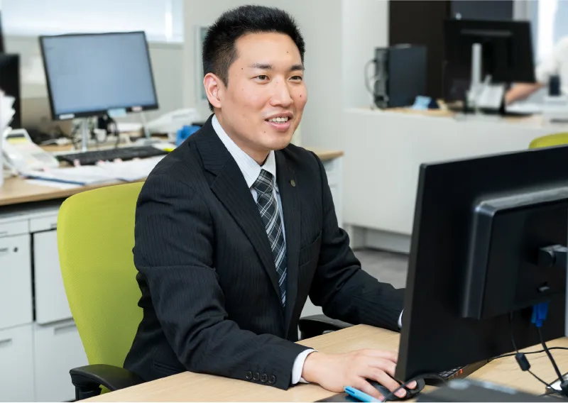 スーツ姿でパソコンに向かい作業をする管理本部 情報管理部のT.Sさん