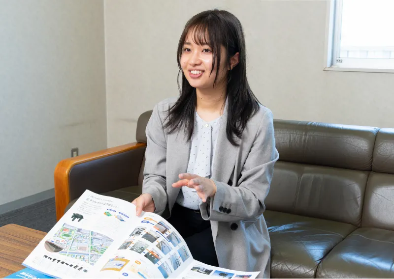 ソファに座り、パンフレットや資料を前にして笑顔で説明するU.Oさん