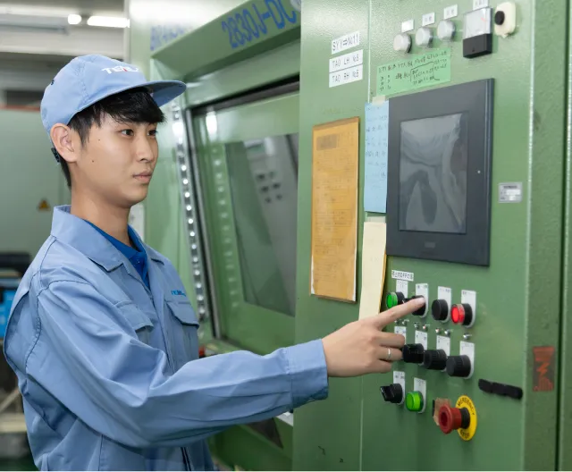 製造ラインの操作盤を操作する組立加工職の社員
