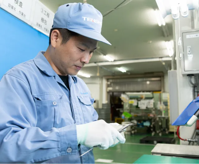 製品を手にとって検査・確認を行う品質管理職の社員