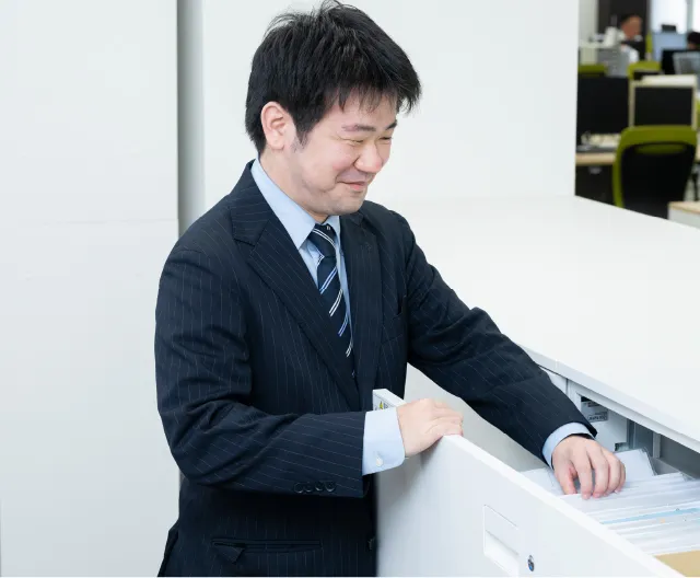 オフィスで書類の整理や確認を行う総務人事職の社員