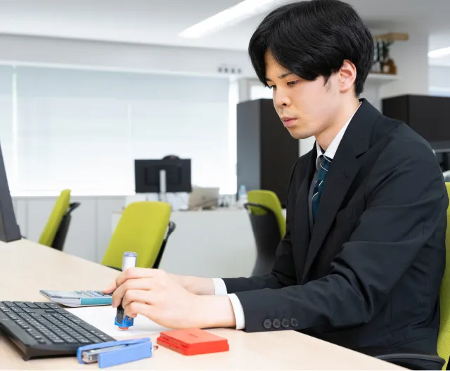 パソコンと書類に向き合い業務を行う経理職の社員