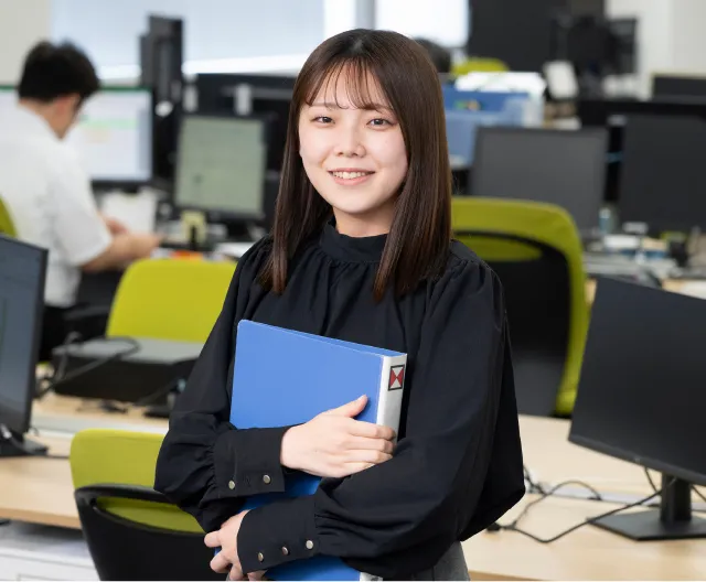 書類を手にして微笑む品質保証職の社員