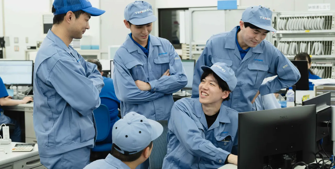 作業服を着て笑顔で打ち合わせをする社員たち