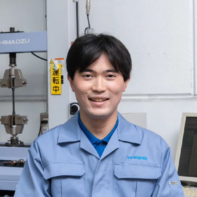 工場内で作業服を着用し微笑む埼玉技術部のK.Kさん